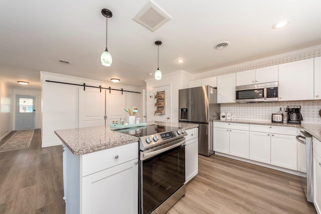 kitchen with white cabinets, decorative light fixtures, stainless steel appliances, and light hardwood / wood-style flooring