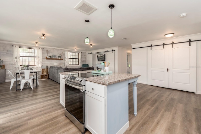 kitchen featuring light wood-type flooring, a barn door, white cabinetry, hanging light fixtures, and stainless steel electric range