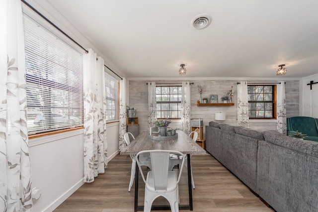 dining area featuring a barn door, hardwood / wood-style flooring, wooden walls, and ornamental molding