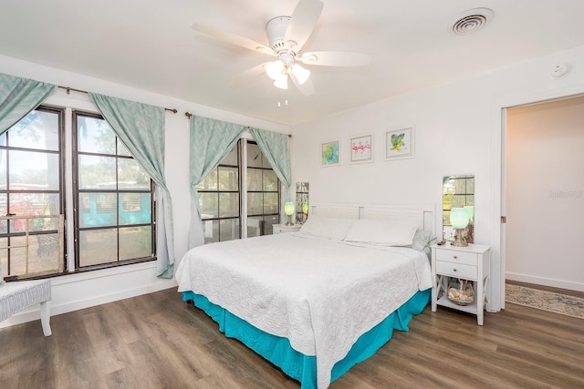 bedroom with ceiling fan, dark wood-type flooring, and multiple windows