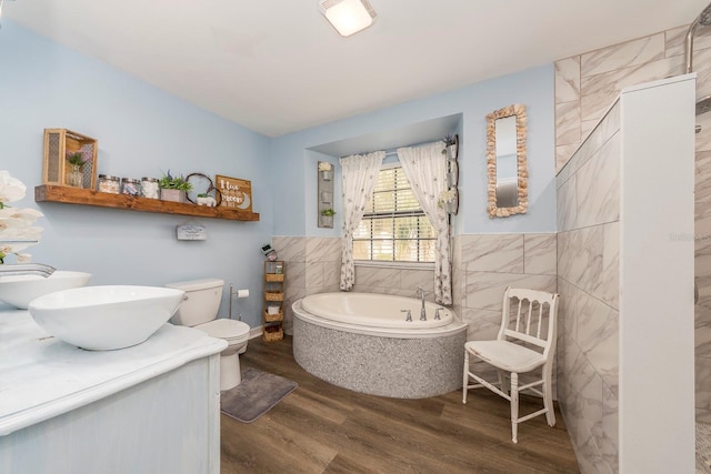 bathroom with a bathtub, vanity, toilet, tile walls, and wood-type flooring