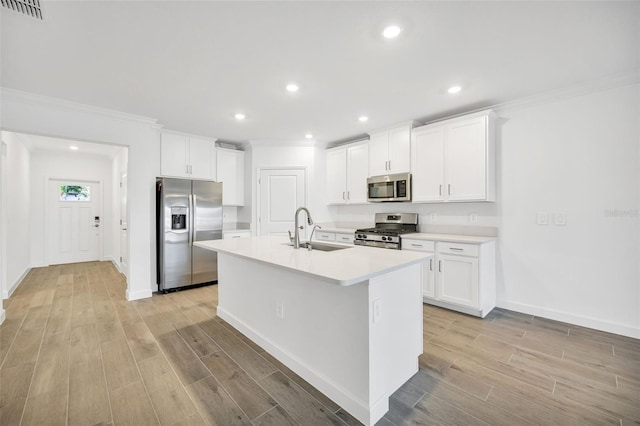 kitchen featuring a center island with sink, crown molding, sink, appliances with stainless steel finishes, and white cabinetry