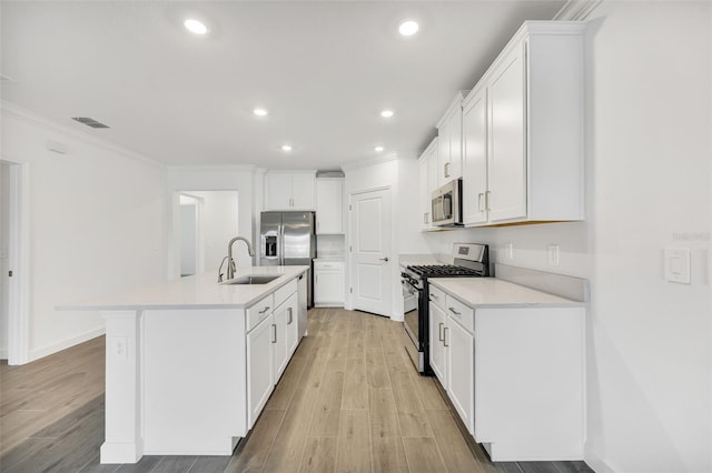 kitchen with white cabinetry, sink, a kitchen island with sink, appliances with stainless steel finishes, and ornamental molding