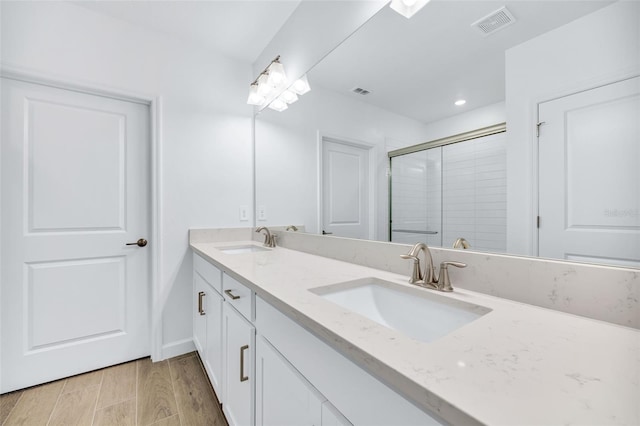 bathroom featuring a shower with door and vanity