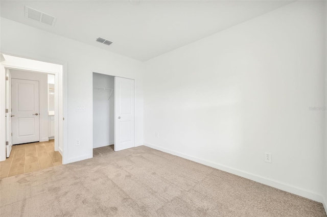 unfurnished bedroom with light colored carpet and a closet