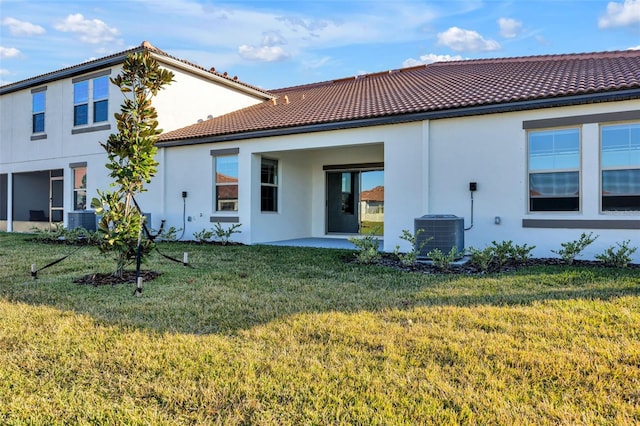 back of property with a patio, a yard, and central AC