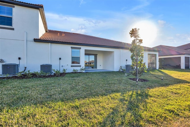 back of house featuring central AC, a patio area, and a lawn