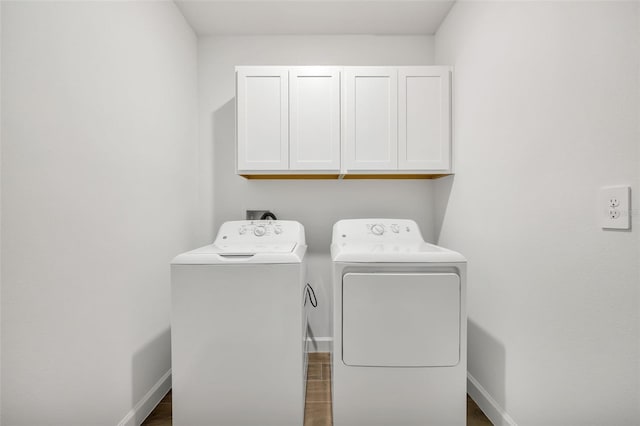 laundry area with washer and dryer, cabinets, and dark wood-type flooring