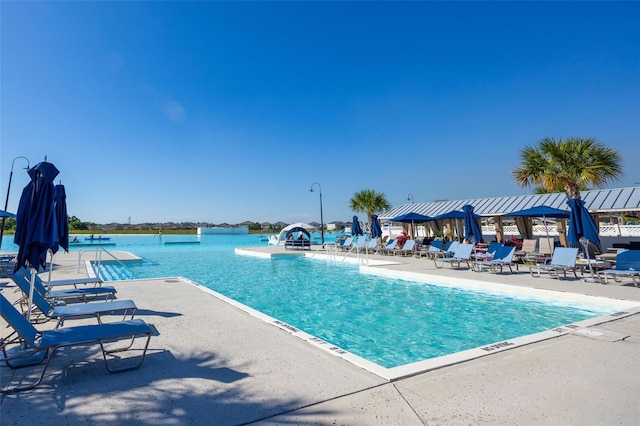 view of swimming pool with a water view, a patio area, and a water slide