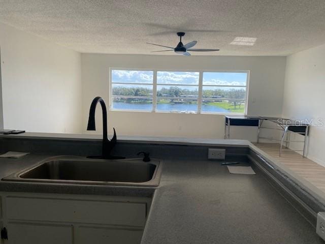 kitchen with carpet floors, sink, a water view, and a textured ceiling