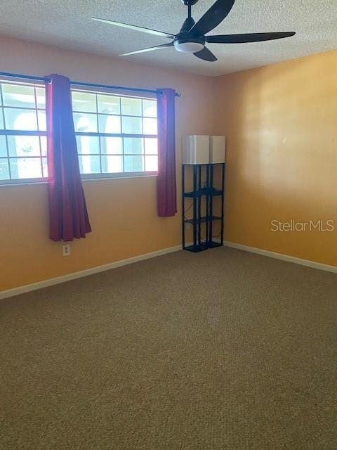 carpeted spare room with ceiling fan and a textured ceiling