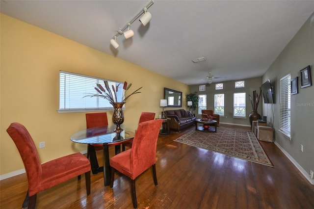 dining area featuring rail lighting, ceiling fan, and dark wood-type flooring