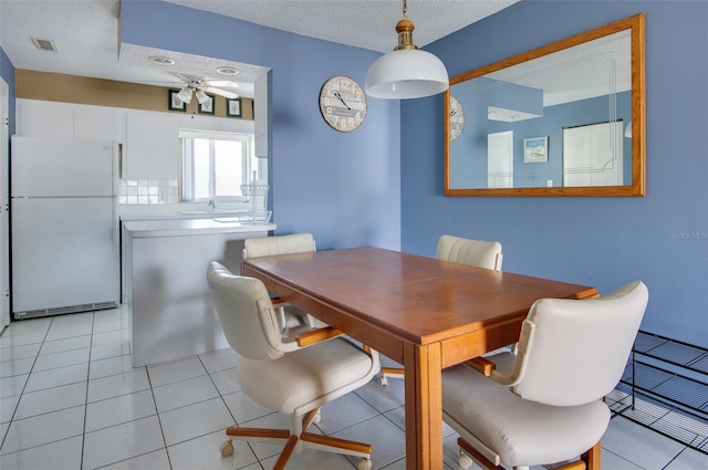 dining room with ceiling fan, light tile patterned floors, and a textured ceiling