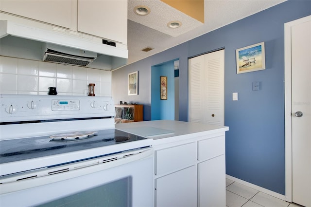 kitchen with electric stove, light tile patterned floors, white cabinets, and a textured ceiling