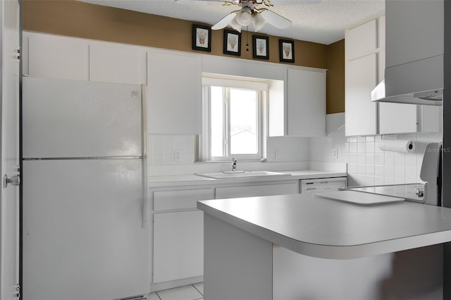 kitchen featuring wall chimney exhaust hood, white appliances, ceiling fan, sink, and white cabinets