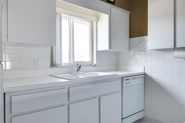 kitchen featuring white dishwasher, white cabinetry, sink, and a wealth of natural light