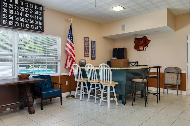 bar with tile patterned flooring and a drop ceiling