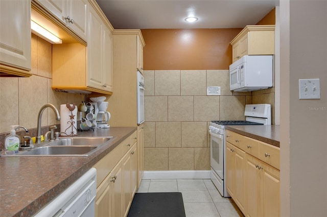 kitchen with light tile patterned floors, white appliances, and sink