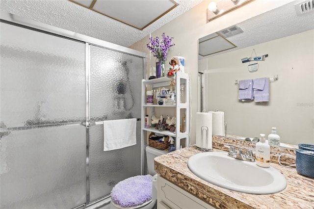 bathroom with a textured ceiling, vanity, toilet, and walk in shower