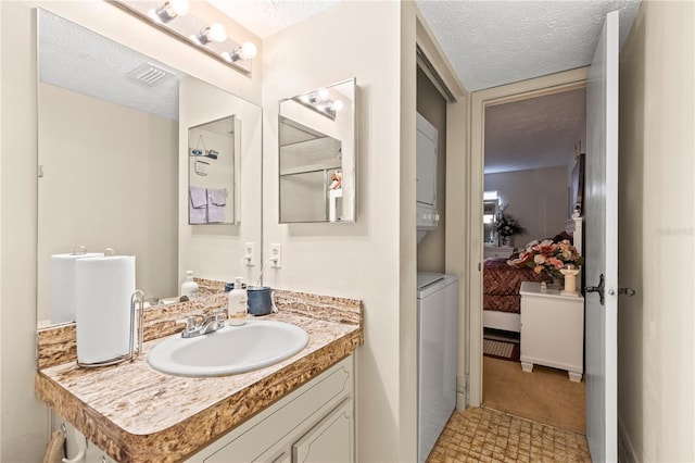 bathroom featuring vanity, a textured ceiling, and stacked washer and dryer