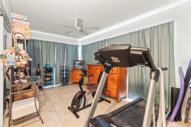 exercise area with ceiling fan, light tile patterned floors, and a textured ceiling