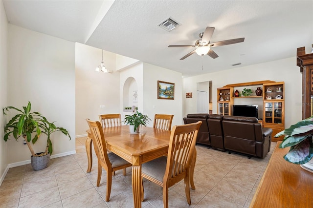 dining room with light tile patterned floors, ceiling fan with notable chandelier, and a textured ceiling