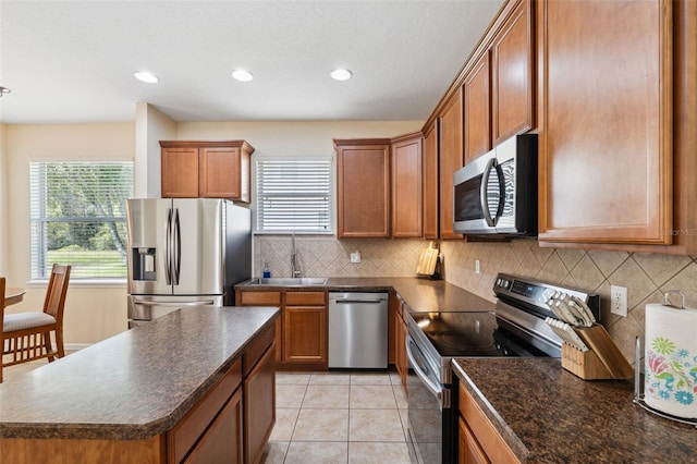 kitchen featuring sink, decorative backsplash, light tile patterned floors, a kitchen island, and stainless steel appliances