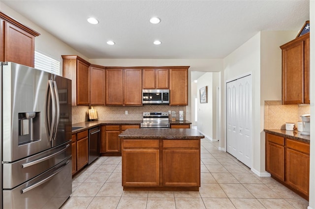 kitchen with tasteful backsplash, a kitchen island, stainless steel appliances, and light tile patterned floors