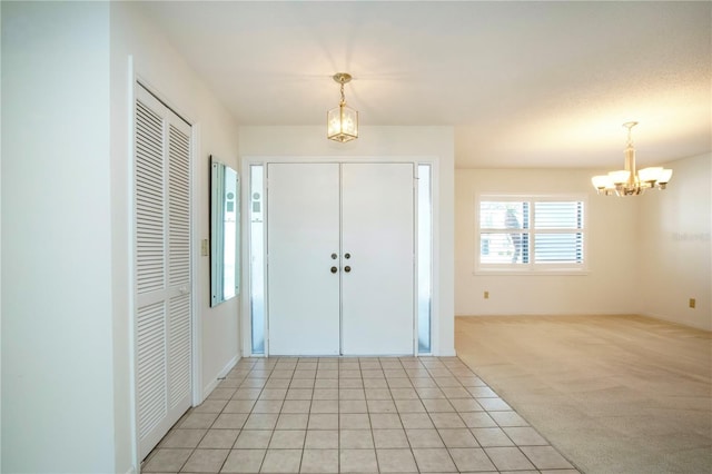 carpeted foyer entrance with a notable chandelier