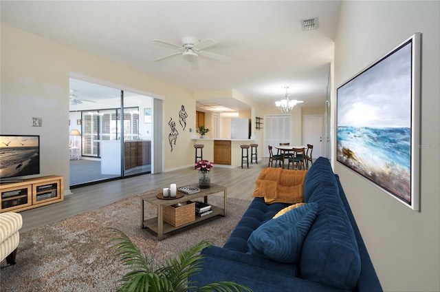 living room with wood-type flooring and ceiling fan with notable chandelier