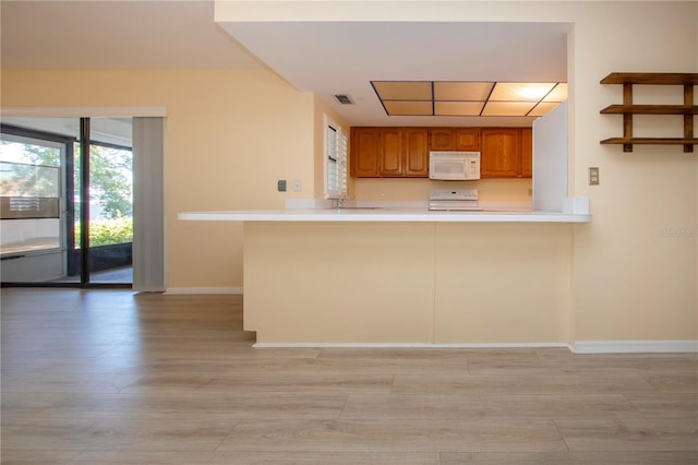 kitchen featuring kitchen peninsula, light wood-type flooring, and range