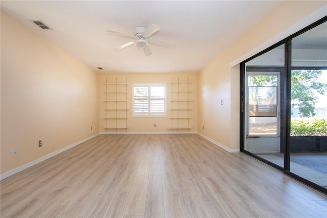 unfurnished room featuring built in shelves, ceiling fan, and light wood-type flooring