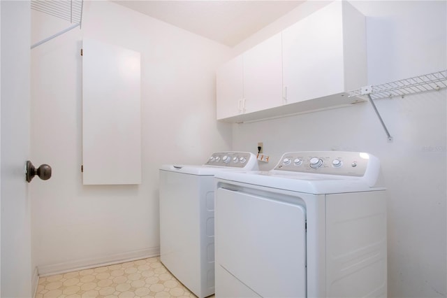 laundry room with separate washer and dryer and cabinets