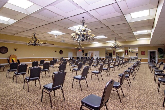 home theater room featuring carpet flooring, a paneled ceiling, and a notable chandelier