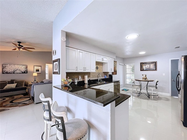 kitchen with white cabinetry, sink, ceiling fan, kitchen peninsula, and a kitchen bar