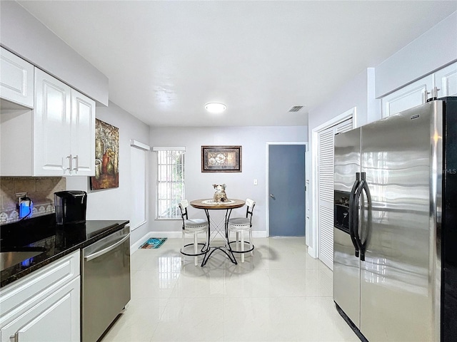 kitchen with backsplash, white cabinets, light tile patterned floors, and appliances with stainless steel finishes