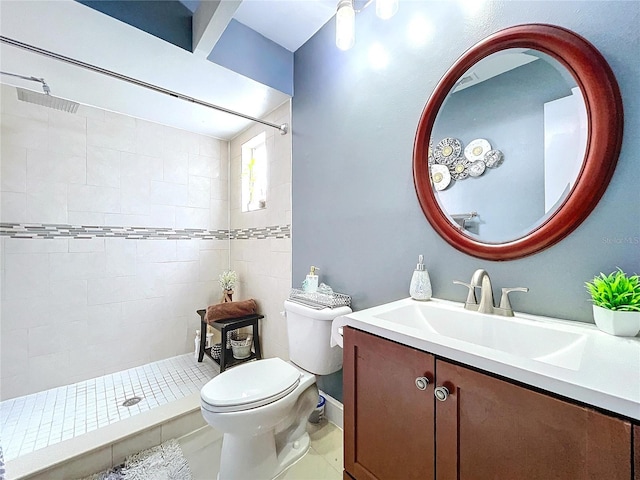 bathroom with tiled shower, tile patterned flooring, vanity, and toilet