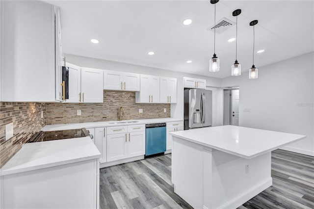 kitchen with a center island, sink, appliances with stainless steel finishes, white cabinets, and light wood-type flooring