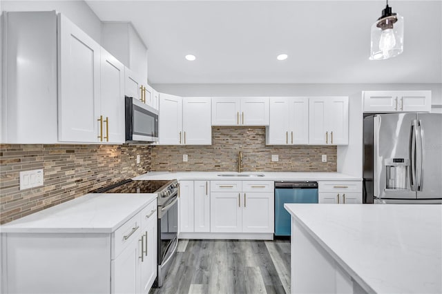 kitchen featuring white cabinets, sink, light hardwood / wood-style flooring, appliances with stainless steel finishes, and decorative light fixtures