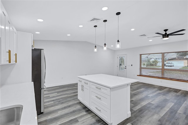 kitchen with stainless steel refrigerator, ceiling fan, a center island, decorative light fixtures, and white cabinets