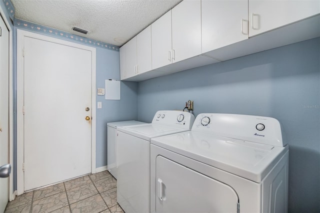 washroom featuring cabinets, a textured ceiling, and separate washer and dryer