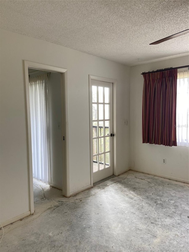 spare room featuring ceiling fan, plenty of natural light, and a textured ceiling