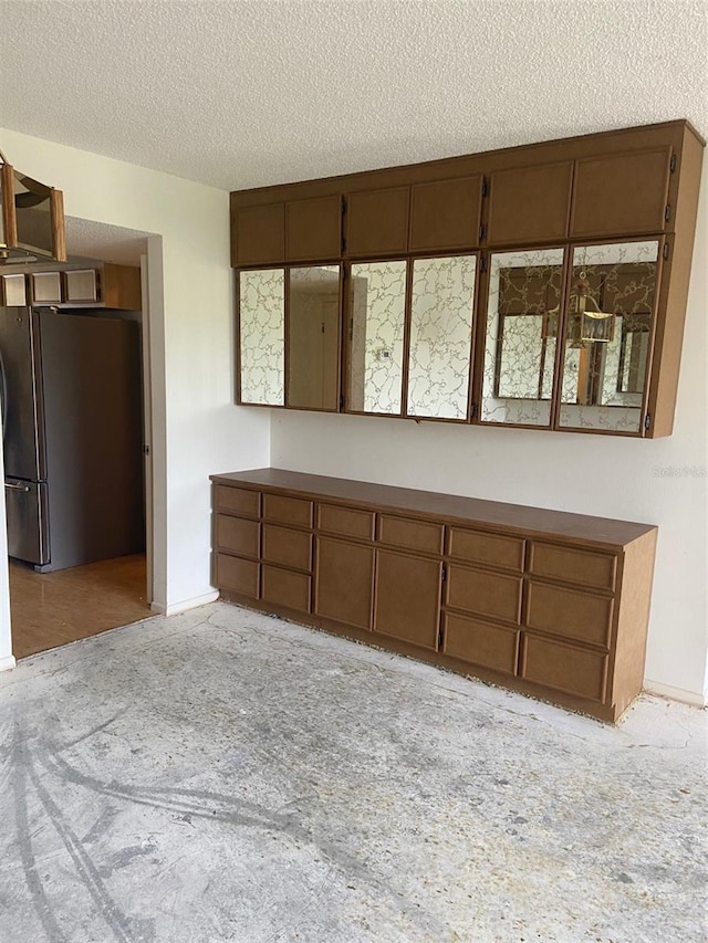 interior space with stainless steel fridge and a textured ceiling