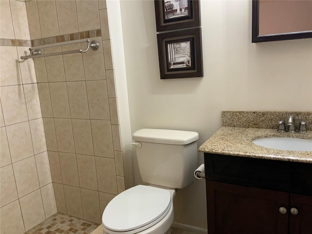 bathroom featuring vanity, toilet, and a tile shower