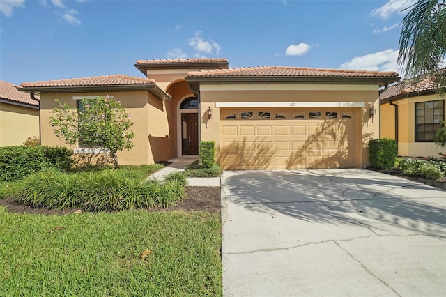 mediterranean / spanish-style house featuring a tiled roof, an attached garage, driveway, and stucco siding