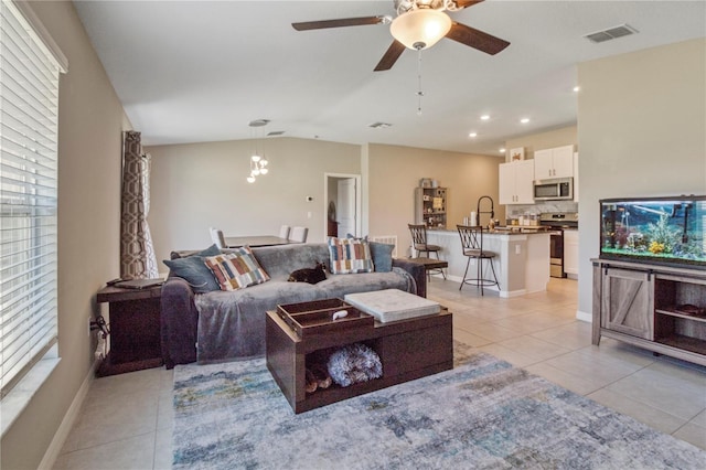 tiled living room with ceiling fan with notable chandelier, lofted ceiling, and sink