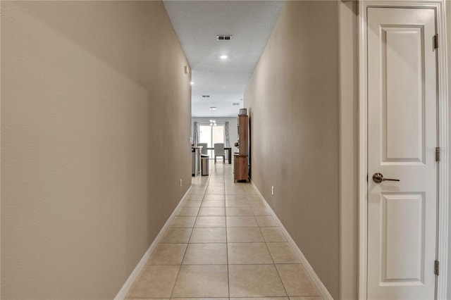 hall featuring a textured ceiling and light tile patterned flooring