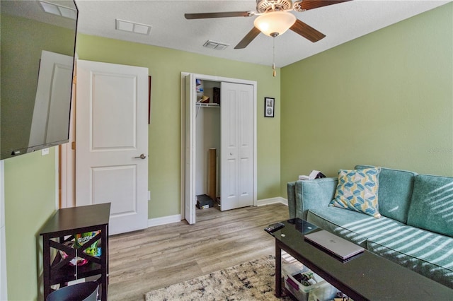 living room with a textured ceiling, light hardwood / wood-style floors, and ceiling fan