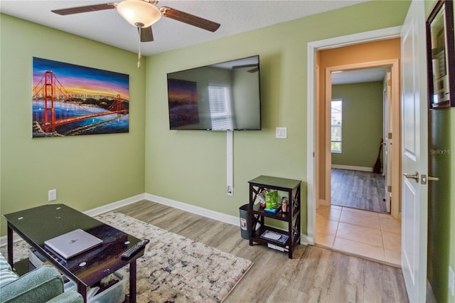 living room with light wood-type flooring, ceiling fan, and a healthy amount of sunlight