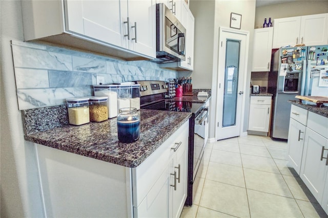 kitchen featuring white cabinets, dark stone countertops, light tile patterned floors, appliances with stainless steel finishes, and tasteful backsplash